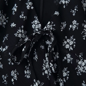 Slim fit black floral dress with deep V-neckline and decorative bow tie detail