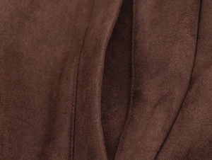 Macro shot of dark brown faux suede jacket fabric showing soft texture and precision stitching