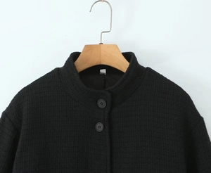 Detailed close-up of textured black stand collar jacket with single-breasted buttons