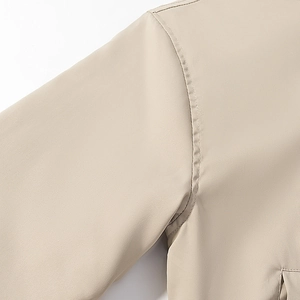 Detailed close-up of stitching on light beige hooded jacket with high-quality fabric texture