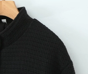 Detailed view of women's black waffle textured jacket with stand collar and button detail