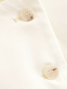 Détail macro de boutons en résine marbrée sur une veste courte couleur crème