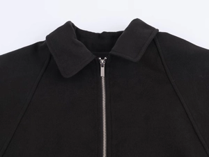 Detailed macro view of the black lapel collar and silver metal zipper on wool coat