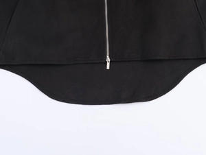 Detail shot of the curved high-low hem and metallic zipper on a black fashion coat
