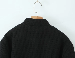 Close-up of black waffle knit texture and stand collar of a long sleeve jacket