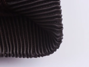 Primo piano della giacca in pelle marrone scuro con pieghe a soffietto e texture