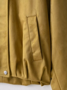 Detailed macro view of mustard yellow suede jacket fabric with metallic snap button