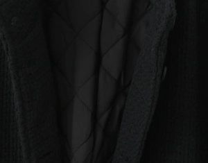 Detail of black tweed jacket featuring internal diamond quilted lining and warm fabric