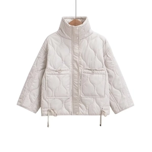 Detail view of cream quilted jacket featuring high collar, large pockets and adjustable drawstrings
