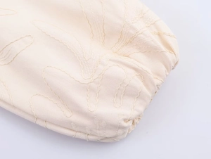 Dettaglio del ricamo delicato e trama saia sul polsino di una giacca fashion beige