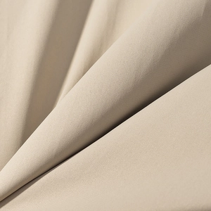 Macro shot of beige hooded cotton jacket fabric showing fine mesh grid texture and softness