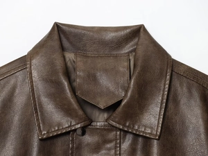 Detail of dark brown leather jacket featuring notched lapels and reinforced shoulder stitching