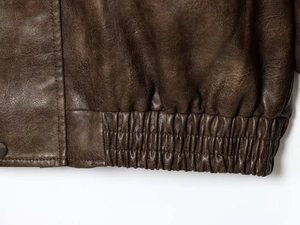 Detail of deep brown PU leather jacket featuring elastic hem and metal snap button