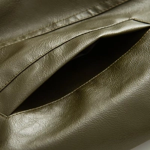 Detailed macro view of olive green faux leather jacket pocket with fine texture and stitching