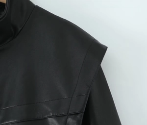 Détail de la veste noire en similicuir avec col montant et coutures précises aux épaules