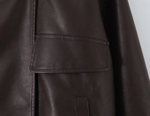 Close-up of side pocket flap and double stitching detail on dark brown PU leather jacket
