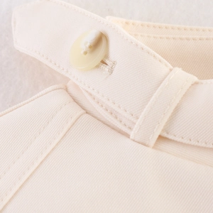 Dettaglio della giacca in twill color crema con bottone in resina e cuciture rifinite