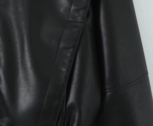 Gros plan détaillé de la texture du cuir PU noir et des coutures précises sur la veste
