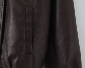 Close-up of deep brown PU leather jacket showing pocket stitching and grain texture