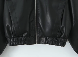 Détail du blouson en PU noir avec poches zippées argentées et ourlet élastique à la taille