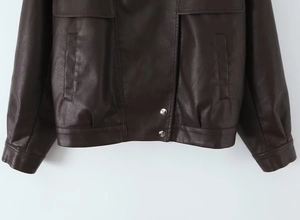 Detail of dark brown PU leather jacket featuring metallic snap buttons and textured pocket