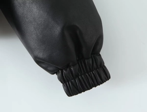 Détail de la manche d'une veste en similicuir noir avec poignet élastique et texture