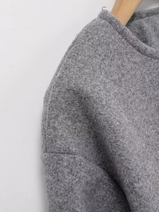 Close-up of high-quality grey textured wool fabric on a women's crewneck jacket