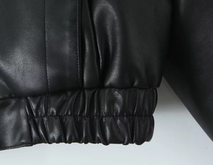 Détail de la veste en cuir PU noir montrant la texture grainée et l'ourlet élastique