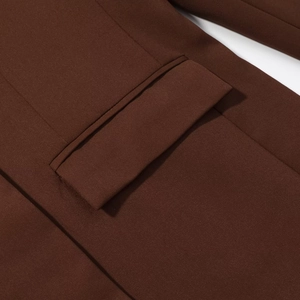 Macro detail of a chocolate brown blazer showing flap pocket and premium fabric stitching