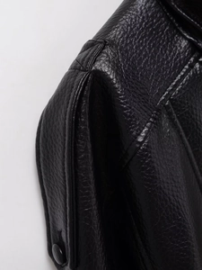 Détail macro d'une veste en similicuir noir montrant le grain et la couture d'épaule