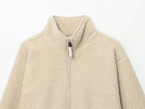 Close-up of soft beige fleece texture and smooth half-zip detail on the high collar jacket