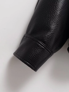 Gros plan du poignet d'une veste en similicuir noir avec texture grainée et double couture