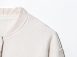Detail of oatmeal wool baseball jacket showing ribbed knit collar and shoulder texture