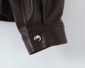 Detailed macro shot of dark brown PU jacket cuff with silver snap button and stitching