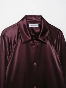 Detailed view of dark purple satin shirt collar with brand label and glossy fabric texture