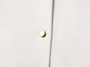 Detailed close-up of wool texture and a single polished gold button on a white jacket