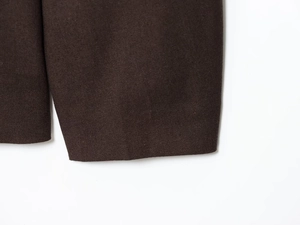 Détail de la texture du tissu tissé marron foncé et des coutures de la veste automne