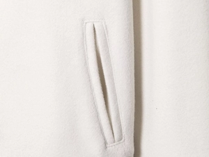 Close-up of the plush wool texture and diagonal pocket detail on white baseball jacket