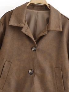 Détail d'une veste en daim marron foncé avec col à revers et boutons texture marbre