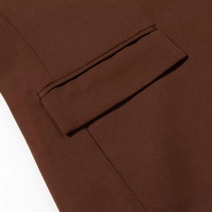Detailed close-up of a flap pocket on a dark brown blazer with precise stitching