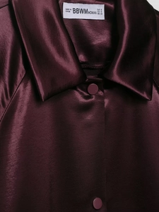 Detail view of burgundy satin jacket featuring a refined collar and premium buttons