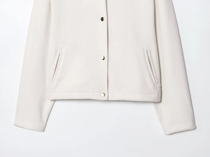 Detail of beige wool jacket showing golden buttons and diagonal side pockets