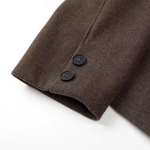 Vue détaillée de la manche d'une veste en laine marron foncé avec deux boutons noirs mats