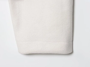 Detailed close-up of the cream wool jacket hem showing high-quality single-needle stitching