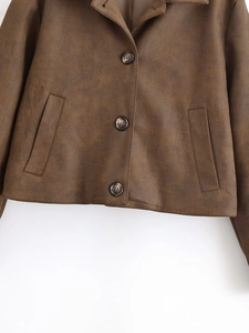 Détail d'une veste courte marron foncé avec boutons marbrés et doublure en tissu lisse