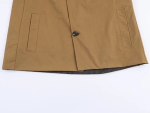 Close-up of khaki jacket hem featuring buttoned flap pockets and striped inner lining
