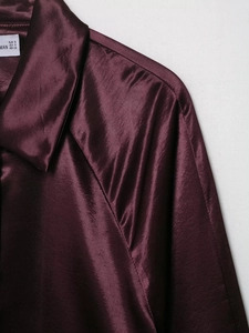 Detail of burgundy satin jacket featuring premium silk texture and classic collar design
