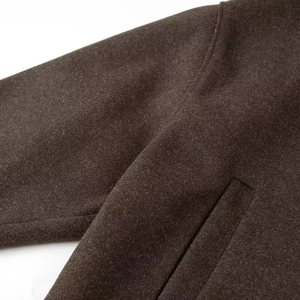 Vue macro du manteau en laine café foncé montrant les coutures et la texture épaisse
