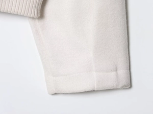 Macro texture of cream wool fabric with ribbed knit detail and premium stitching