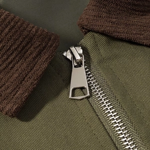 Detailed close-up of olive green fabric with brown ribbed collar and silver metal zipper